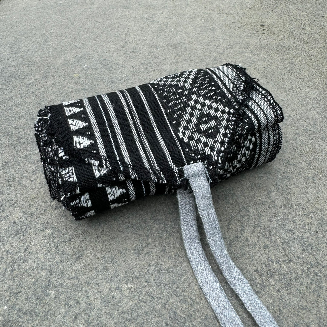 Black and white patterned LARP belt and sash set on concrete surface.