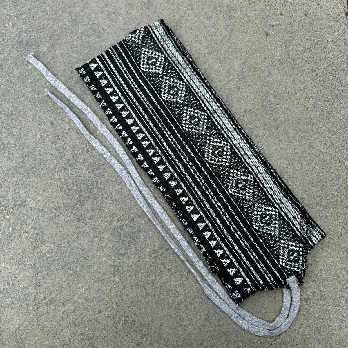 Black and white LARP pirate sash with geometric pattern on flat surface.