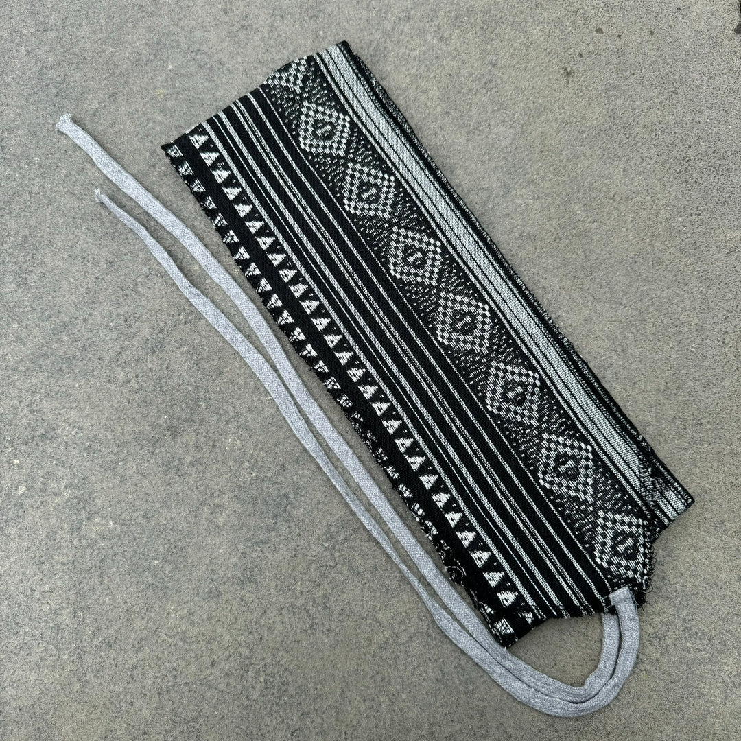 Black and white LARP pirate sash with geometric pattern on flat surface.