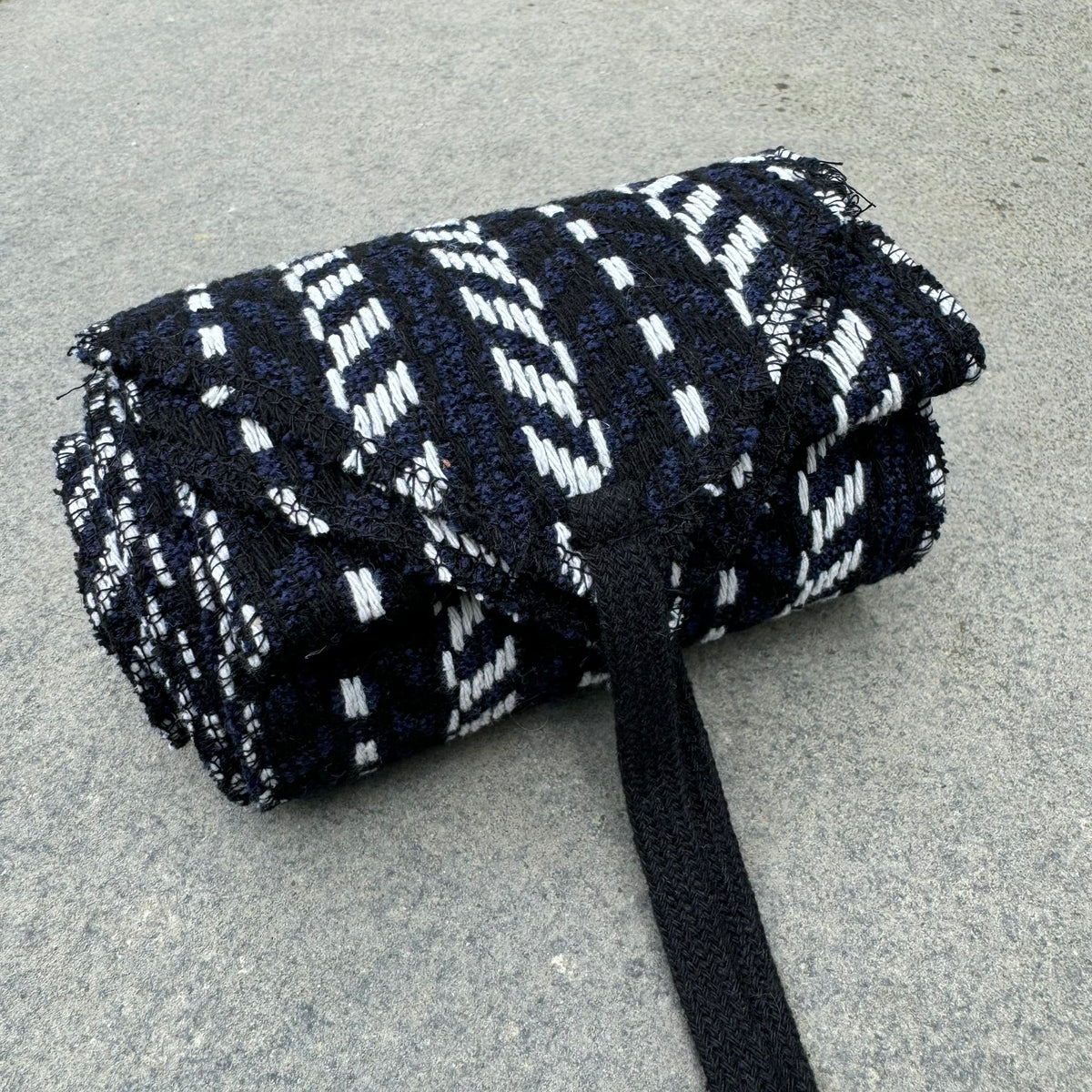 LARP herringbone sash, blue, black, and white knitted wool, rolled up.