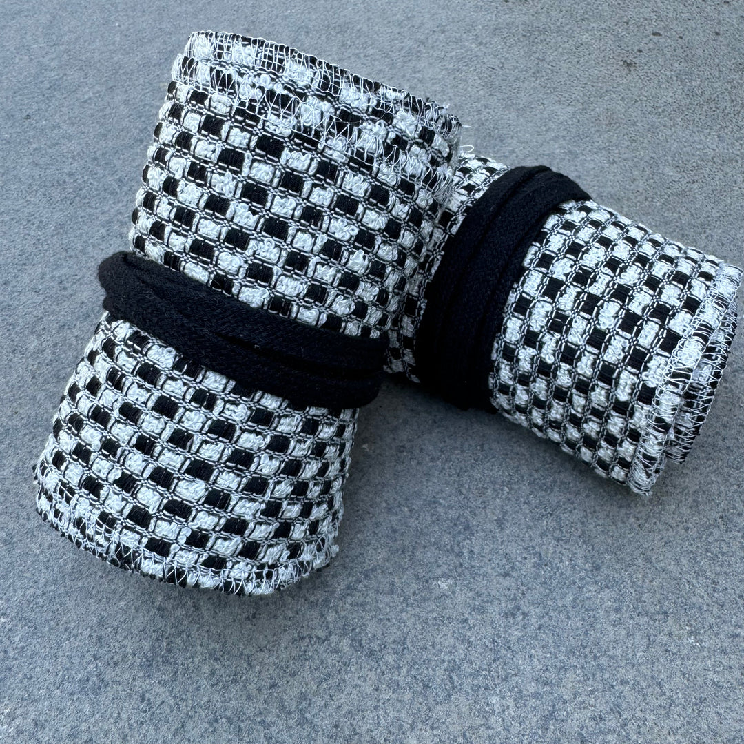 Black and white checkered wool leg wraps for LARP, rolled.