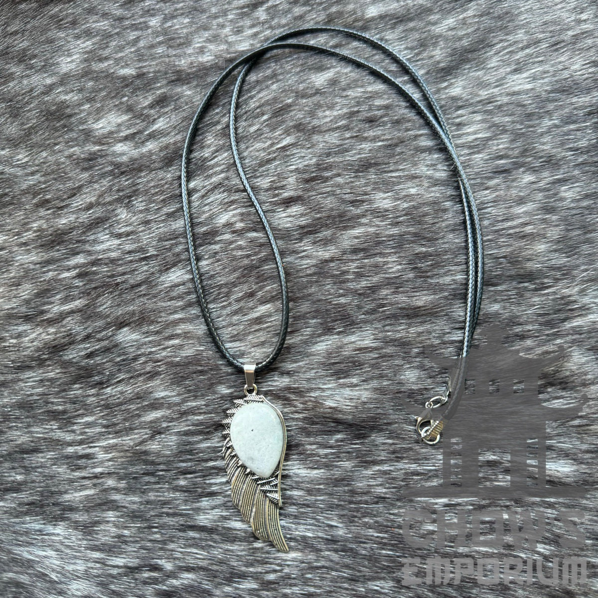 Necklace with silver wing pendant for LARP, laid on textured grey background.