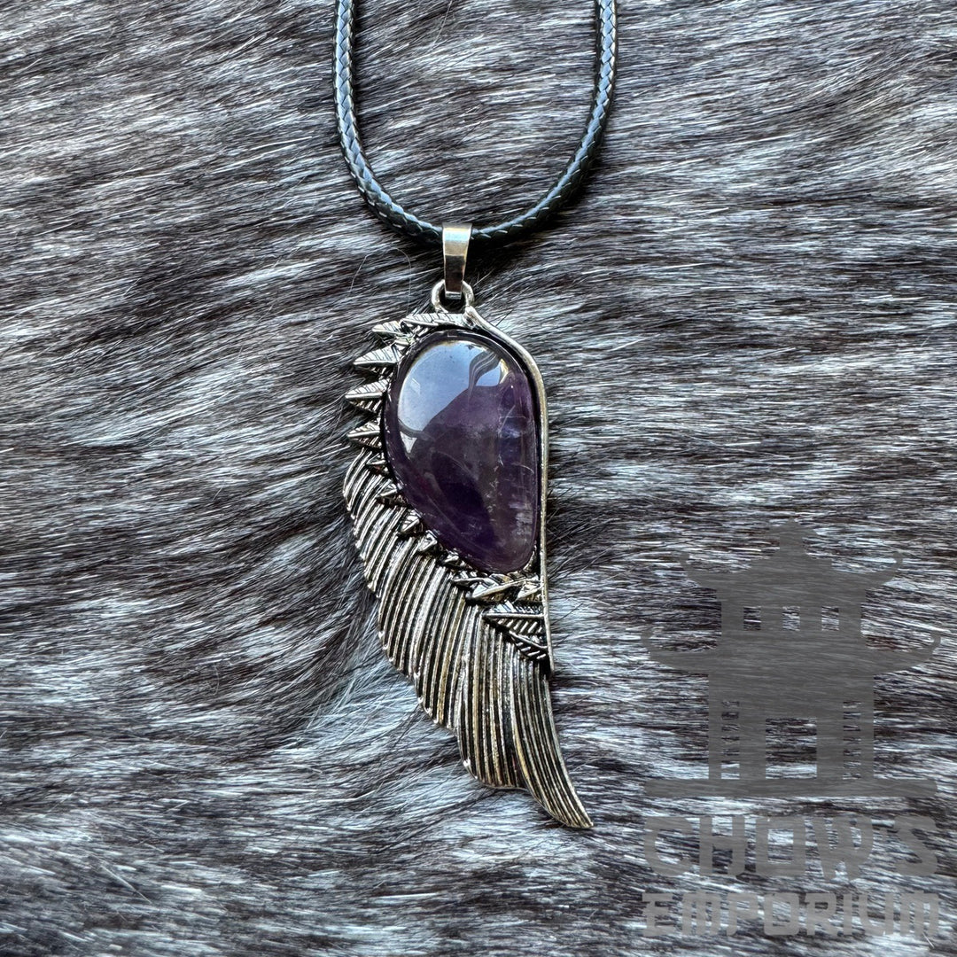 Amethyst and feather necklace, medieval style, on a textured surface.