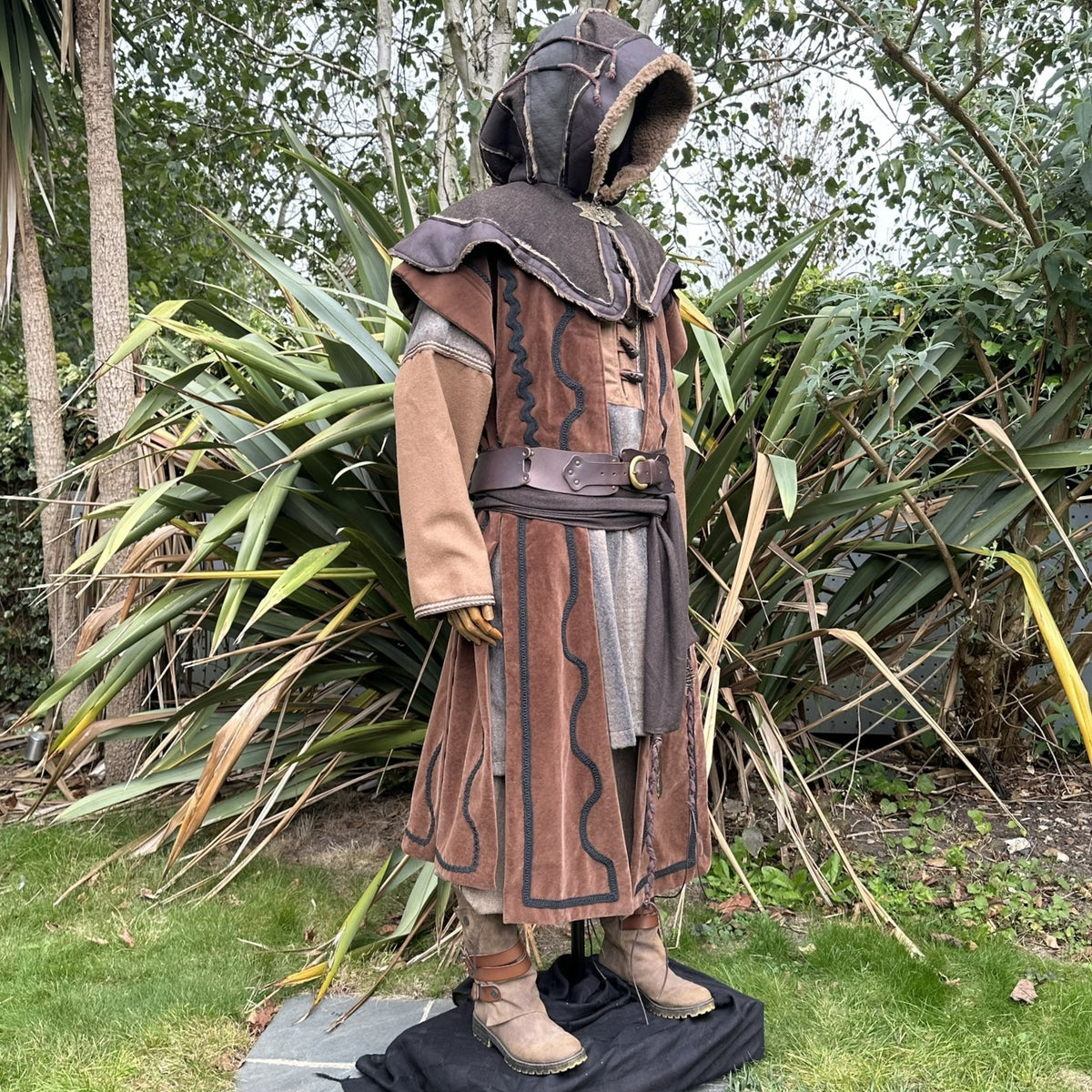 Mannequin in medieval LARP attire with hood, waistcoat, and boots.