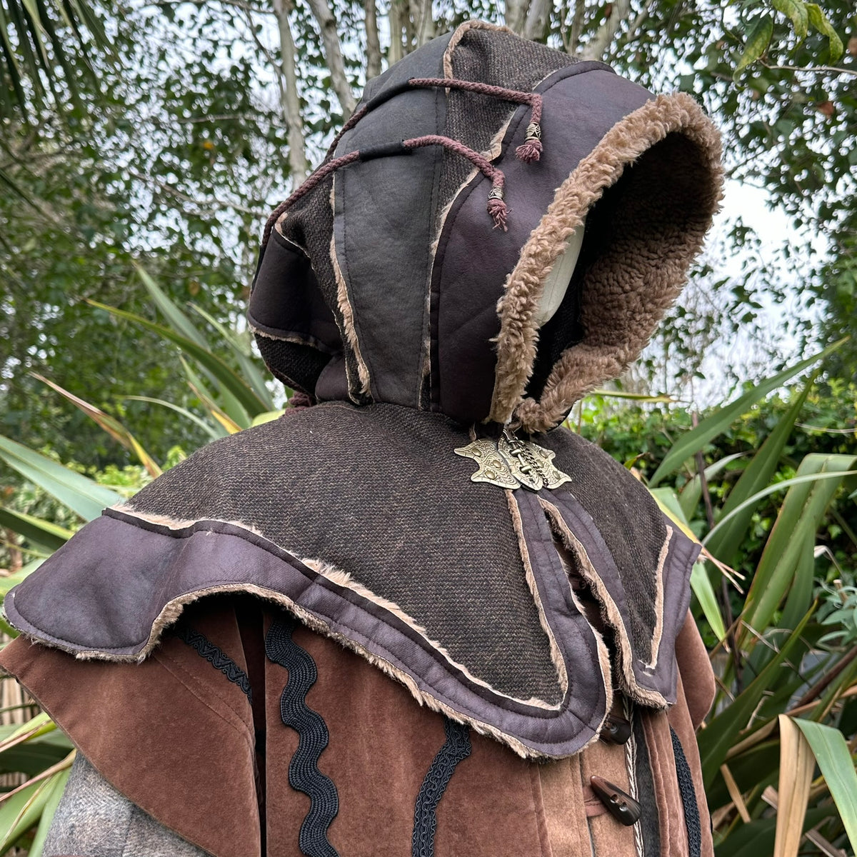 Medieval LARP outfit hood with fur trim, side view, forest backdrop.