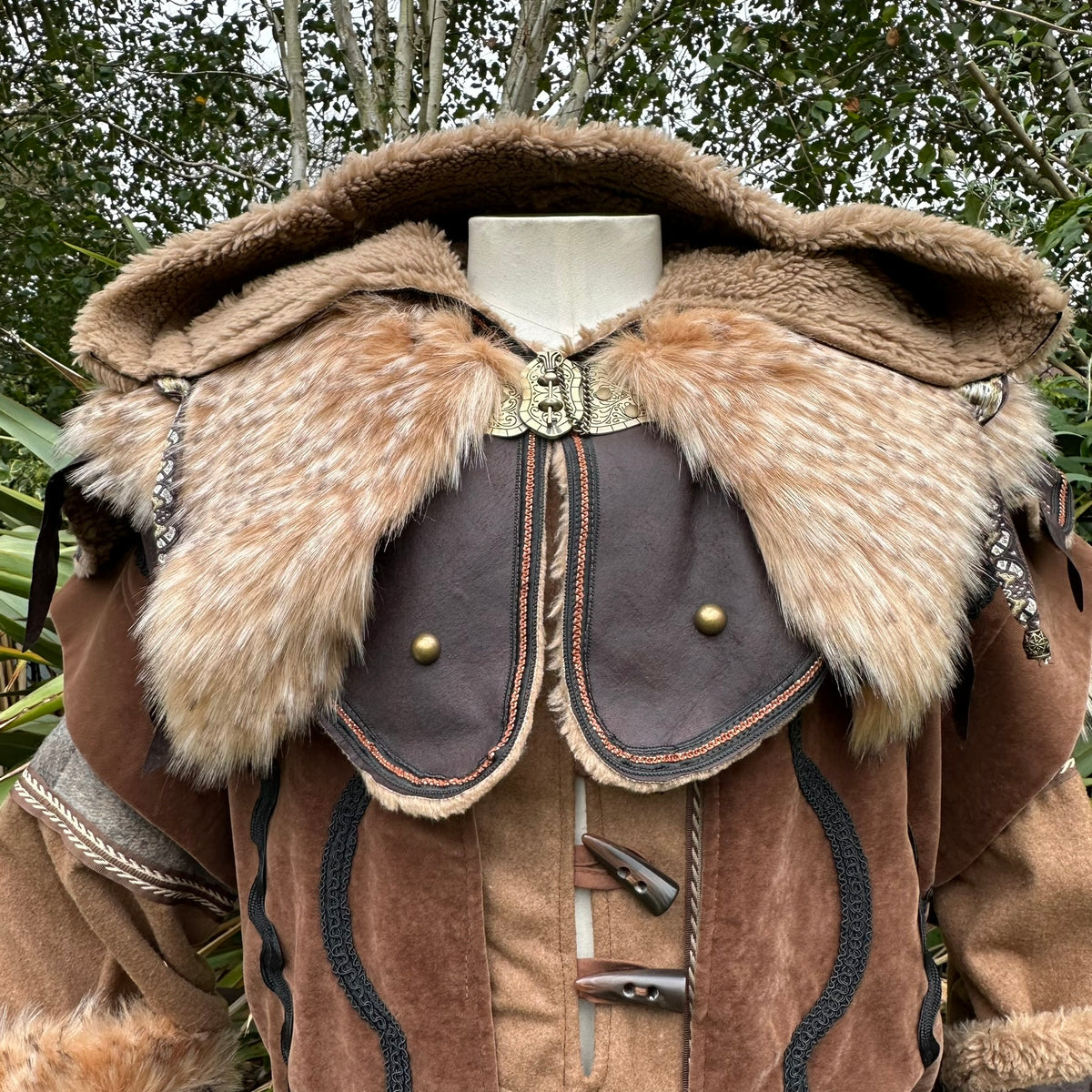 Faux leather LARP hood with gold clasp, brown fur trim, forest backdrop.