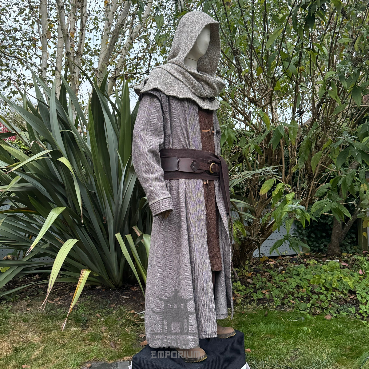 Side profile of LARP mystic healer in hooded robe, nature backdrop.