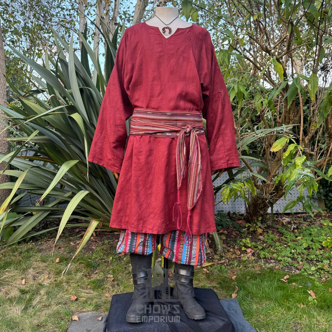 Medieval LARP outfit front view, featuring a red tunic, multi-striped trousers and sash.
