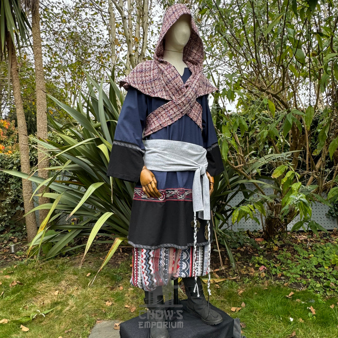 Medieval LARP outfit side view, featuring a blue and black tunic, patterned trousers, and sash.