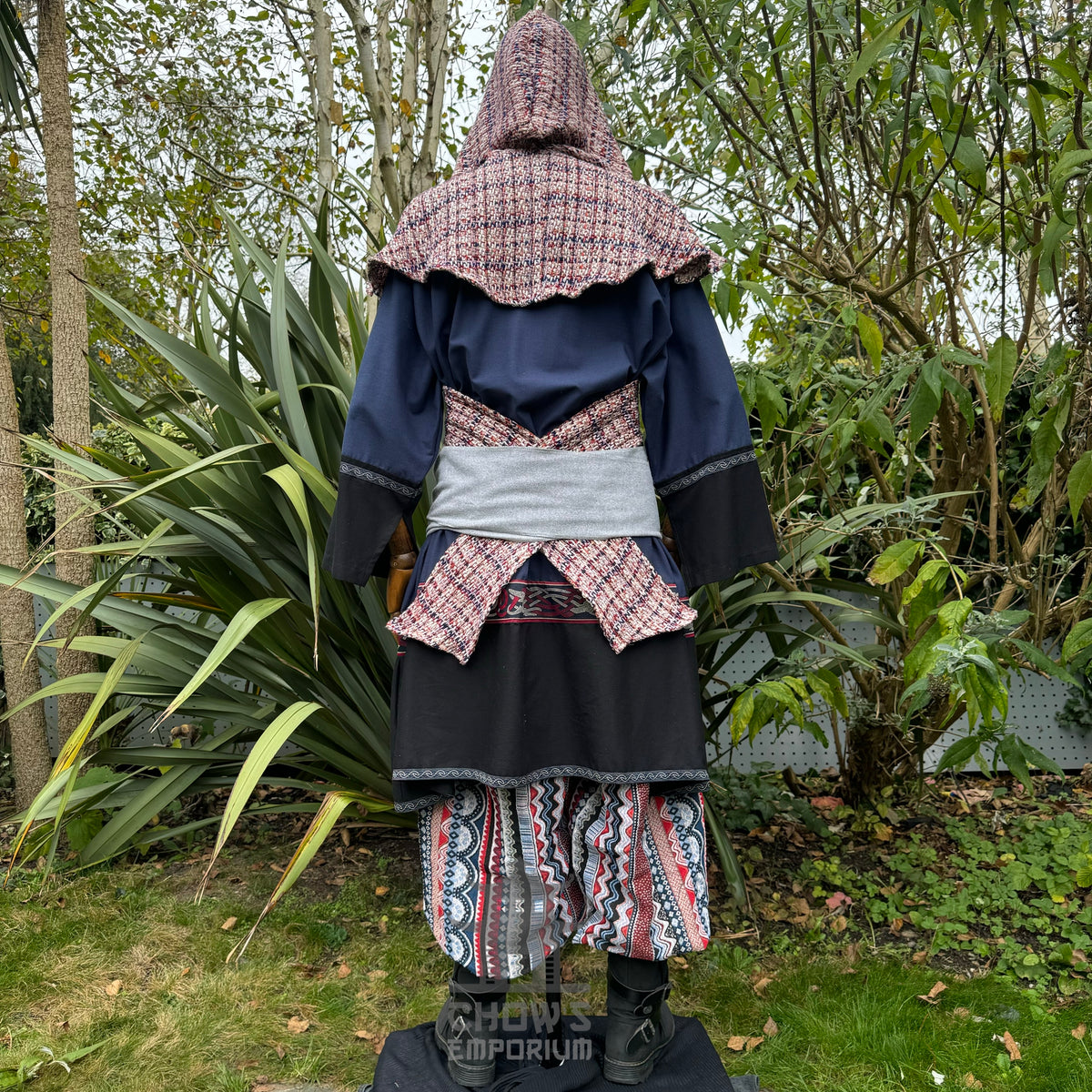 Medieval LARP outfit back view, featuring a blue and black tunic, patterned trousers, and sash.