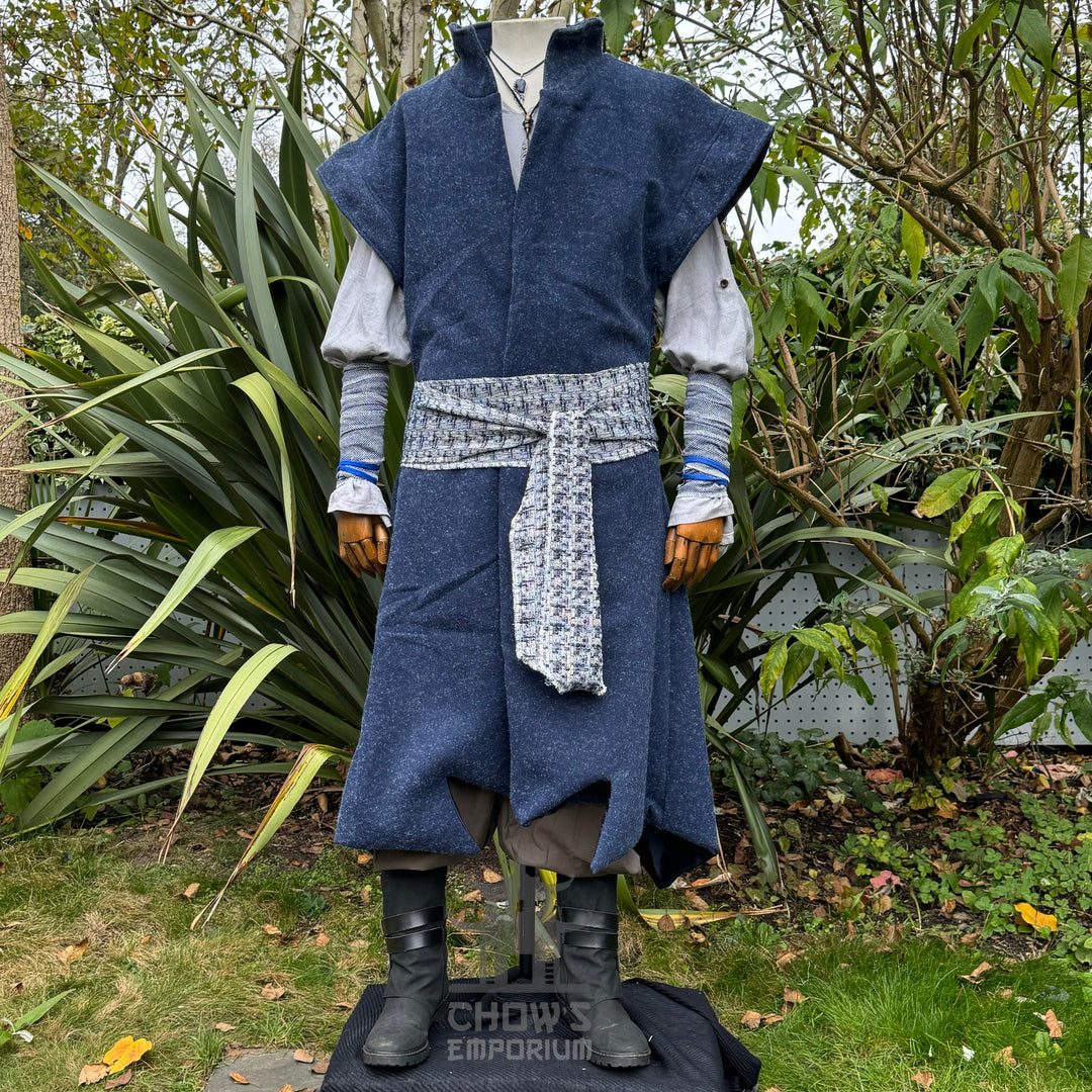 Medieval LARP costume front view, featuring a blue waistcoat, tunic, trousers, arm wraps, sash.