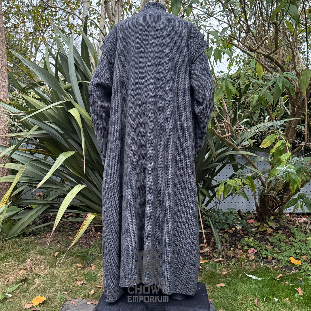 Back view of grey herringbone robe in a LARP medieval garden scene.