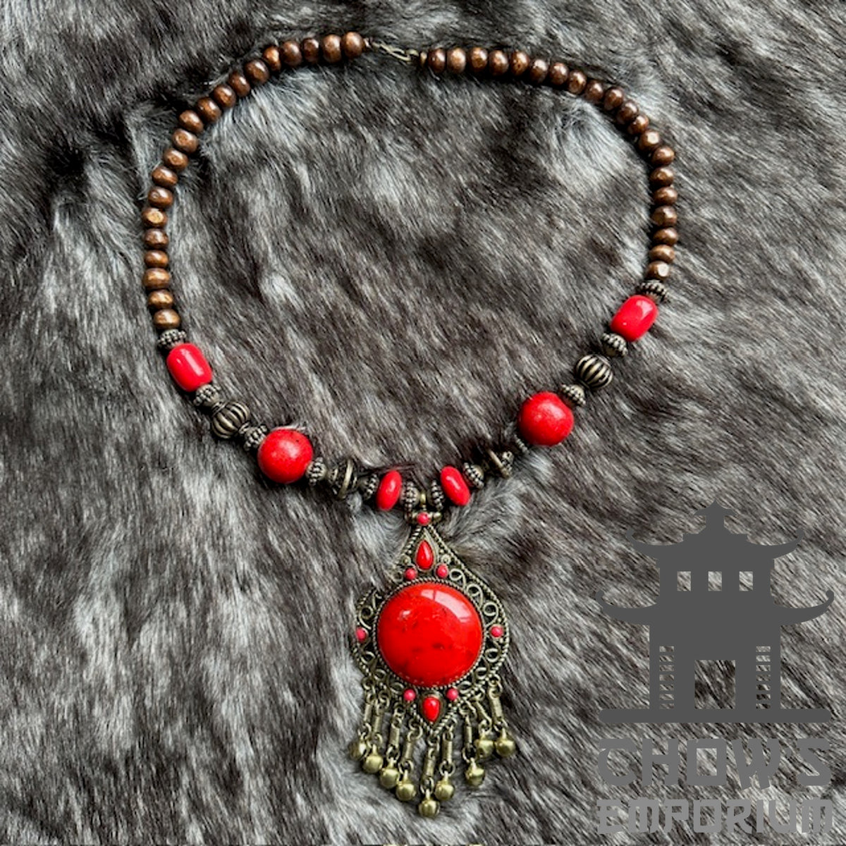 LARP medieval necklace with red beads and ornate pendant on faux fur backdrop.
