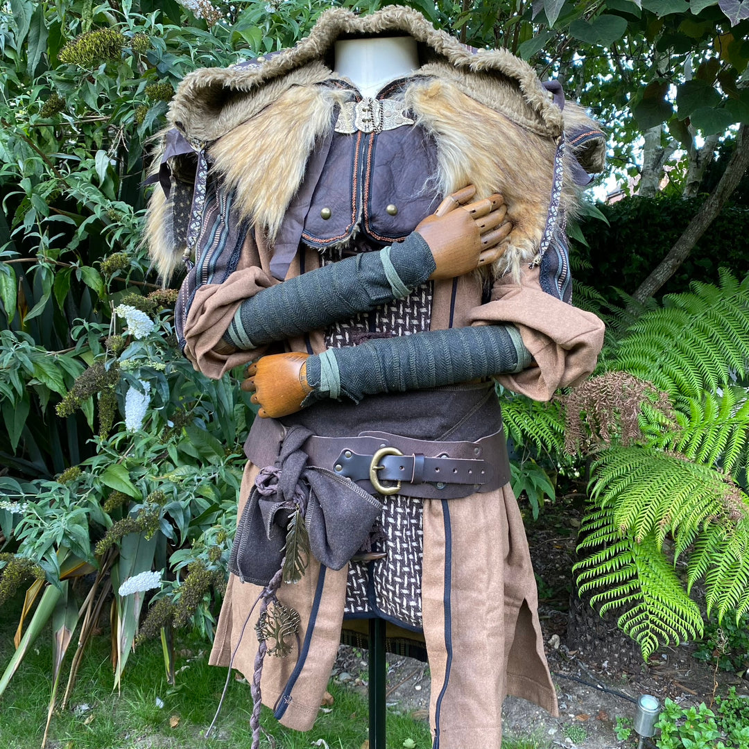 Medieval costume display with green herringbone wraps and fur cloak neckline.