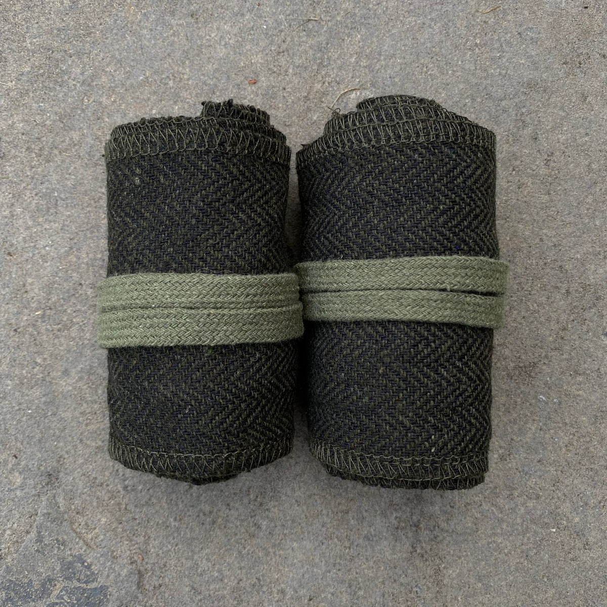 Rolled medieval LARP wraps in green herringbone pattern on stone surface.