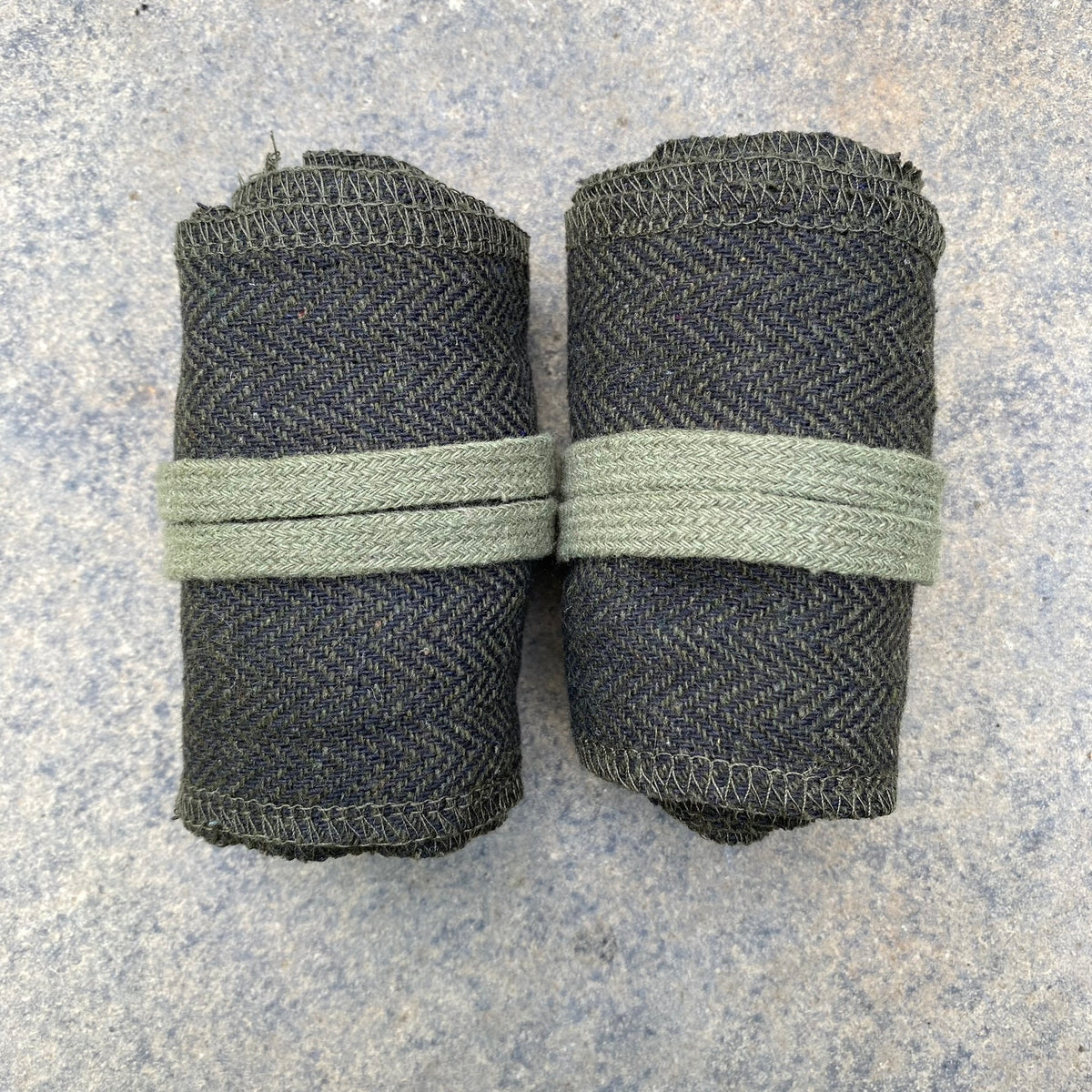Green herringbone medieval wraps rolled up for LARP use, top view.