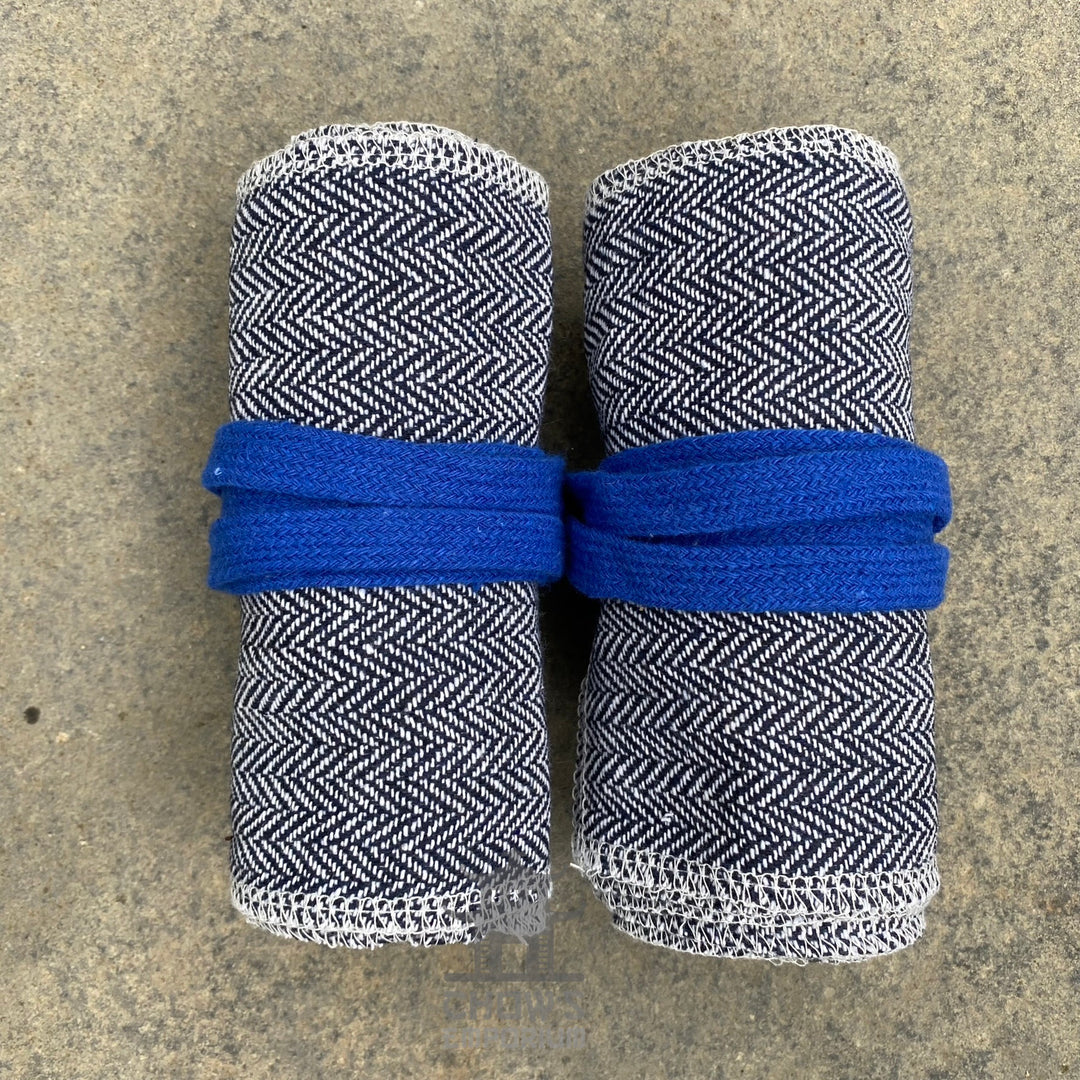 Two rolled black and white herringbone arm wraps, blue ties, top view.