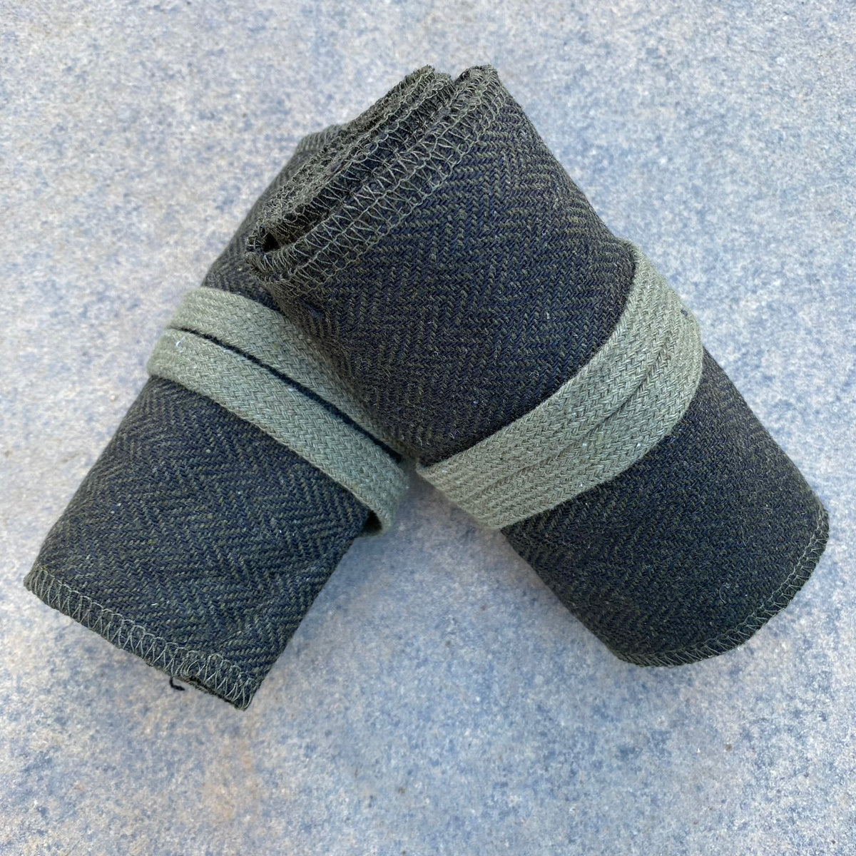 Rolled medieval LARP wraps, green-black herringbone on a stone surface.