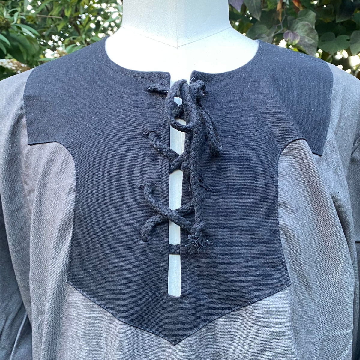 Dark mage LARP shirt with black lace-up detail on grey fabric, close-up view.