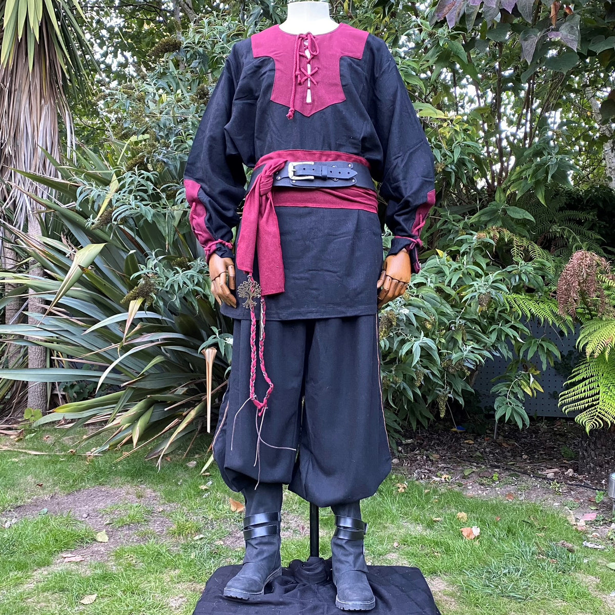 Medieval LARP attire, front view; tunic with red accents, leather belt, boots.