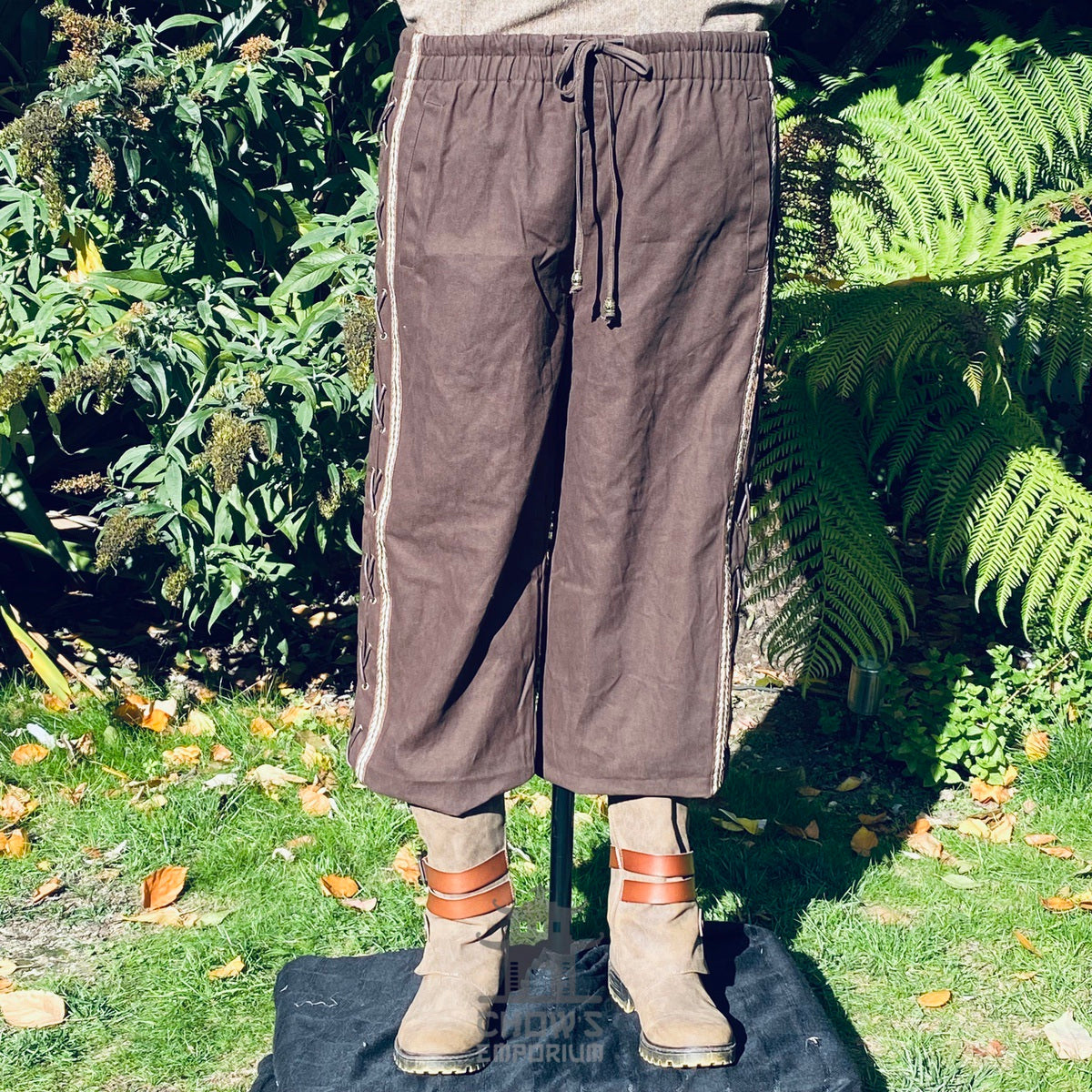 straight-leg medieval trousers in brown cotton with lacing and brading.