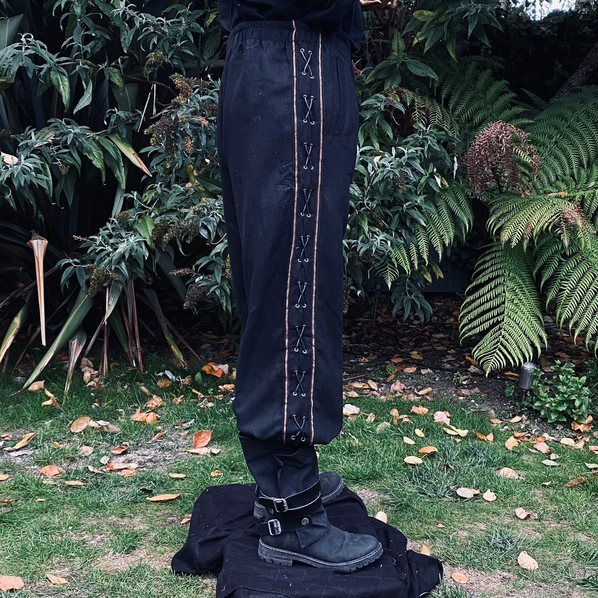Side view of black LARP trousers with lace detail.