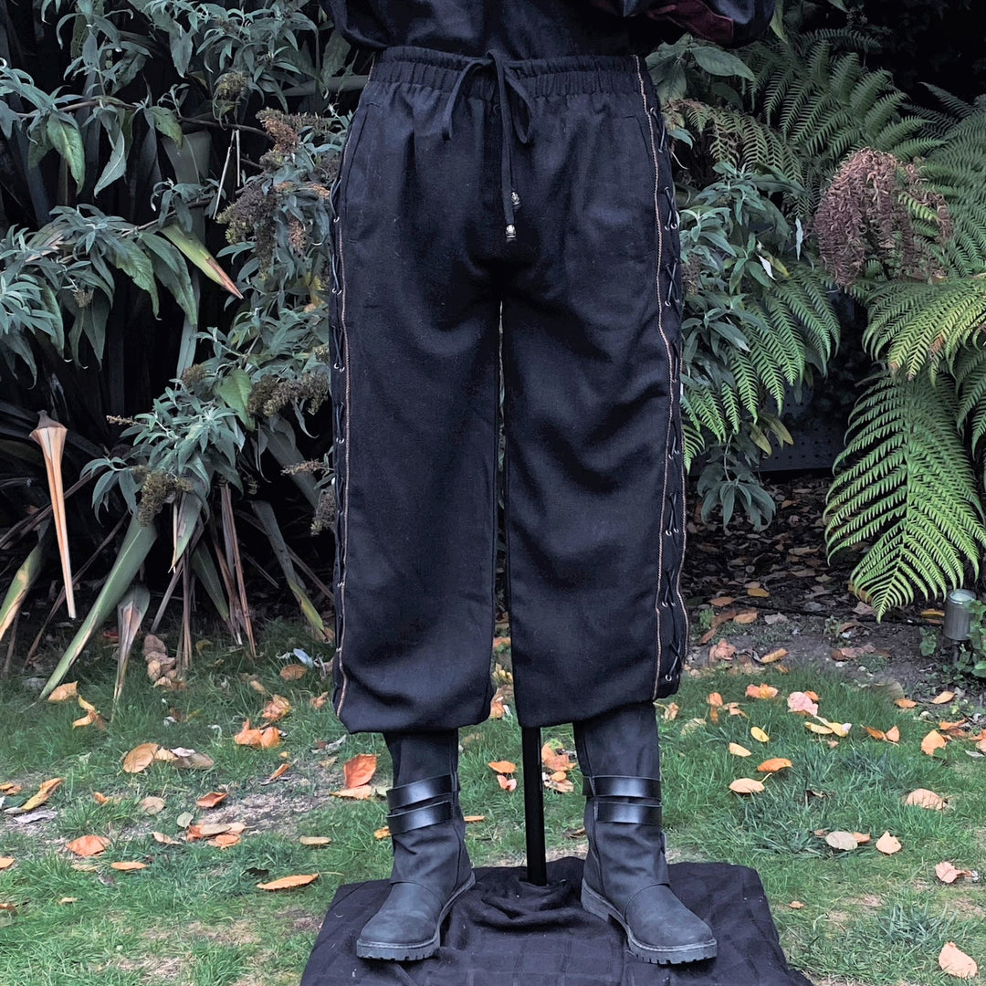 Black LARP pants with side lace detail, front view amidst garden foliage.