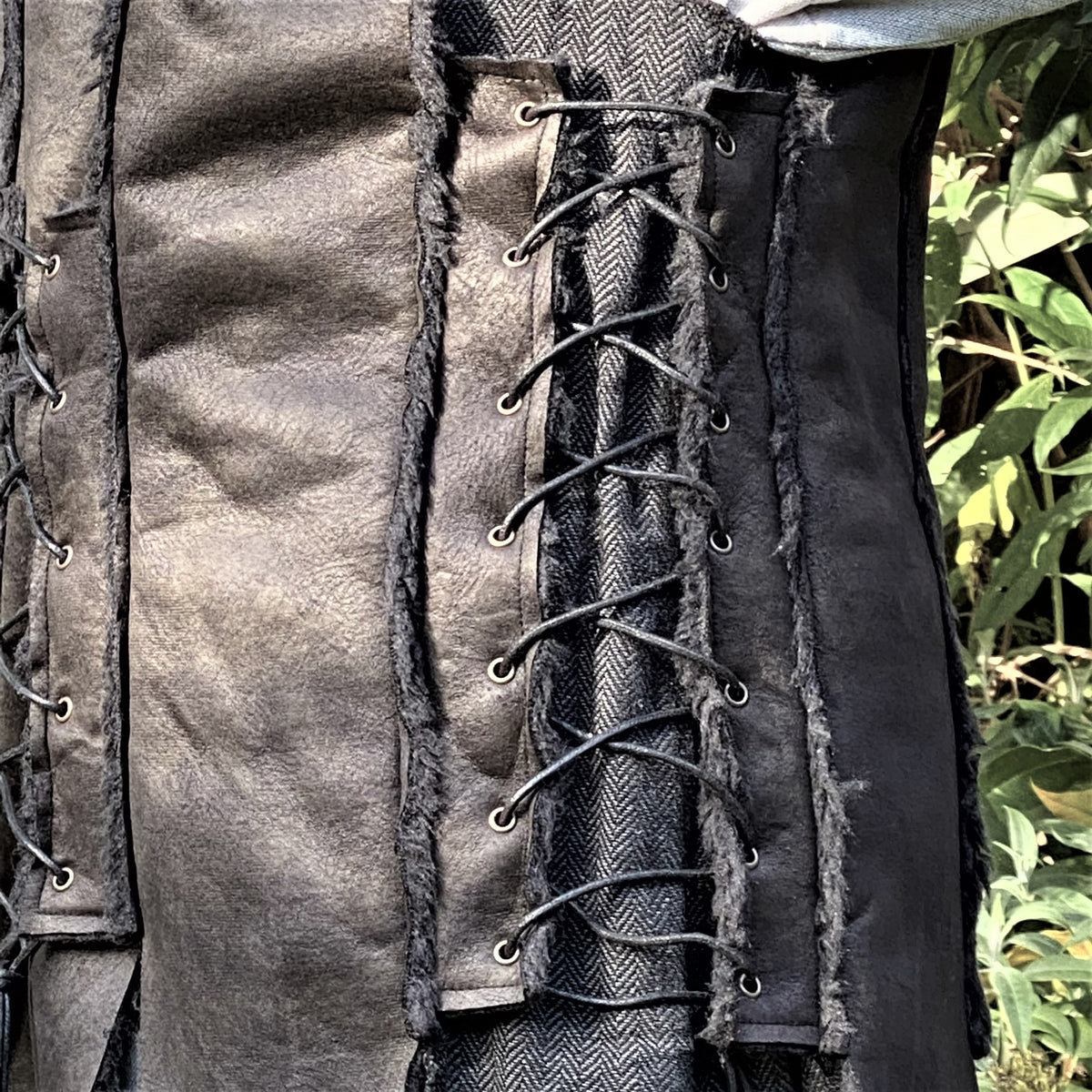 Dark leather and herringbone medieval waistcoat with cord lacing, side view.