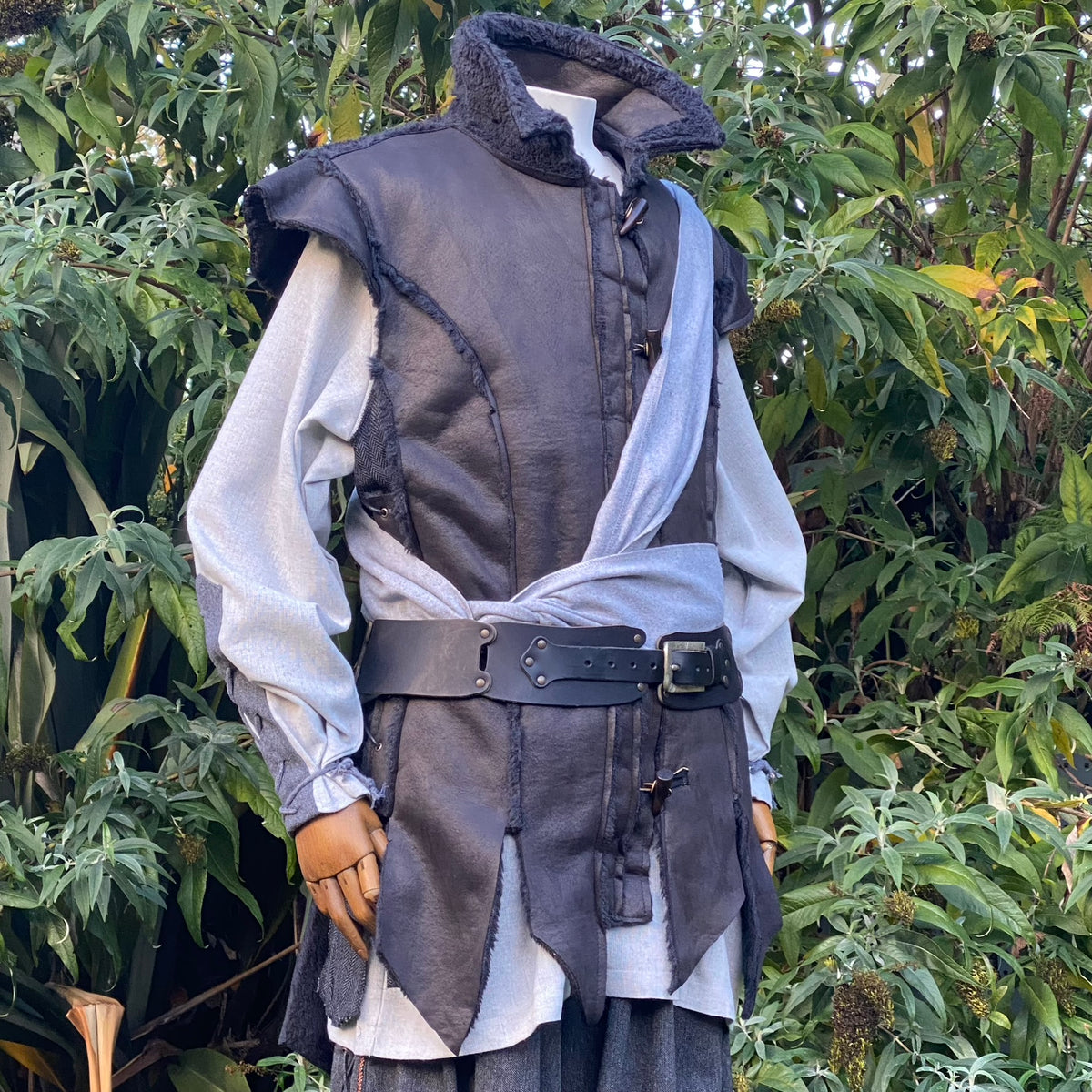Medieval LARP outfit with textured hood, grey sash, and layered belt.
