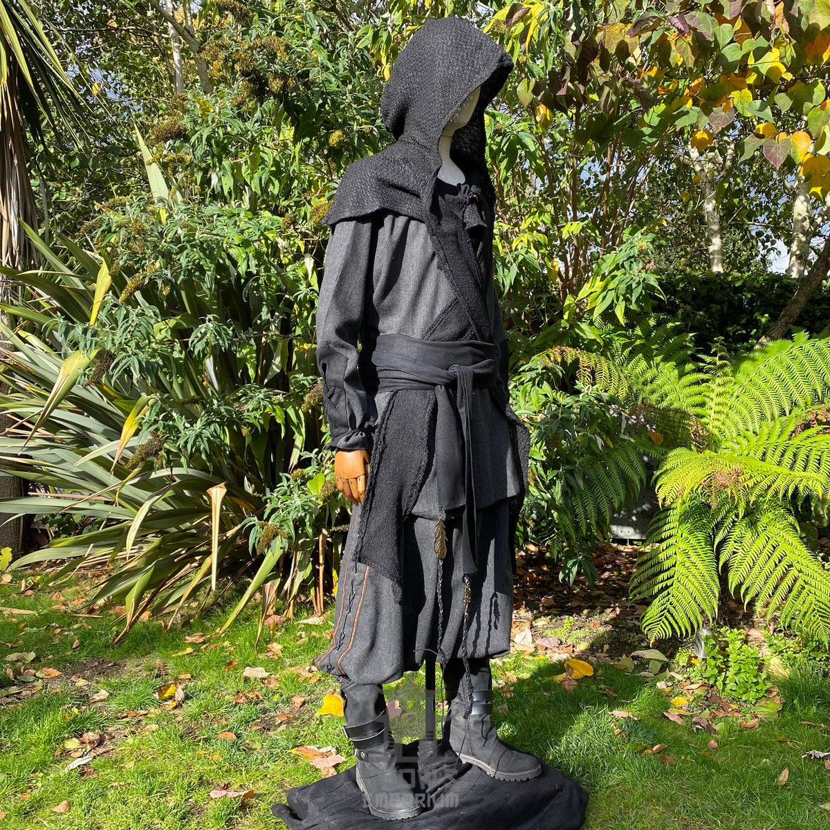 Mannequin wearing black wool hooded cloak in sunny garden for LARP.