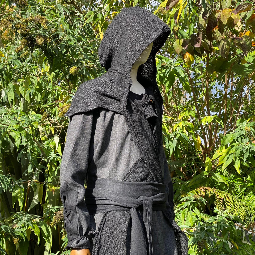 Medieval LARP outfit with hooded mannequin, side view among greenery.