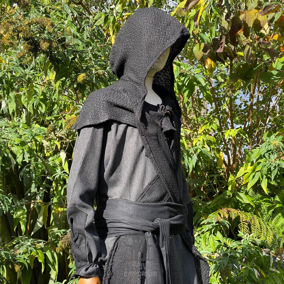 Black wool scarf hood for LARP, side view against leafy background.