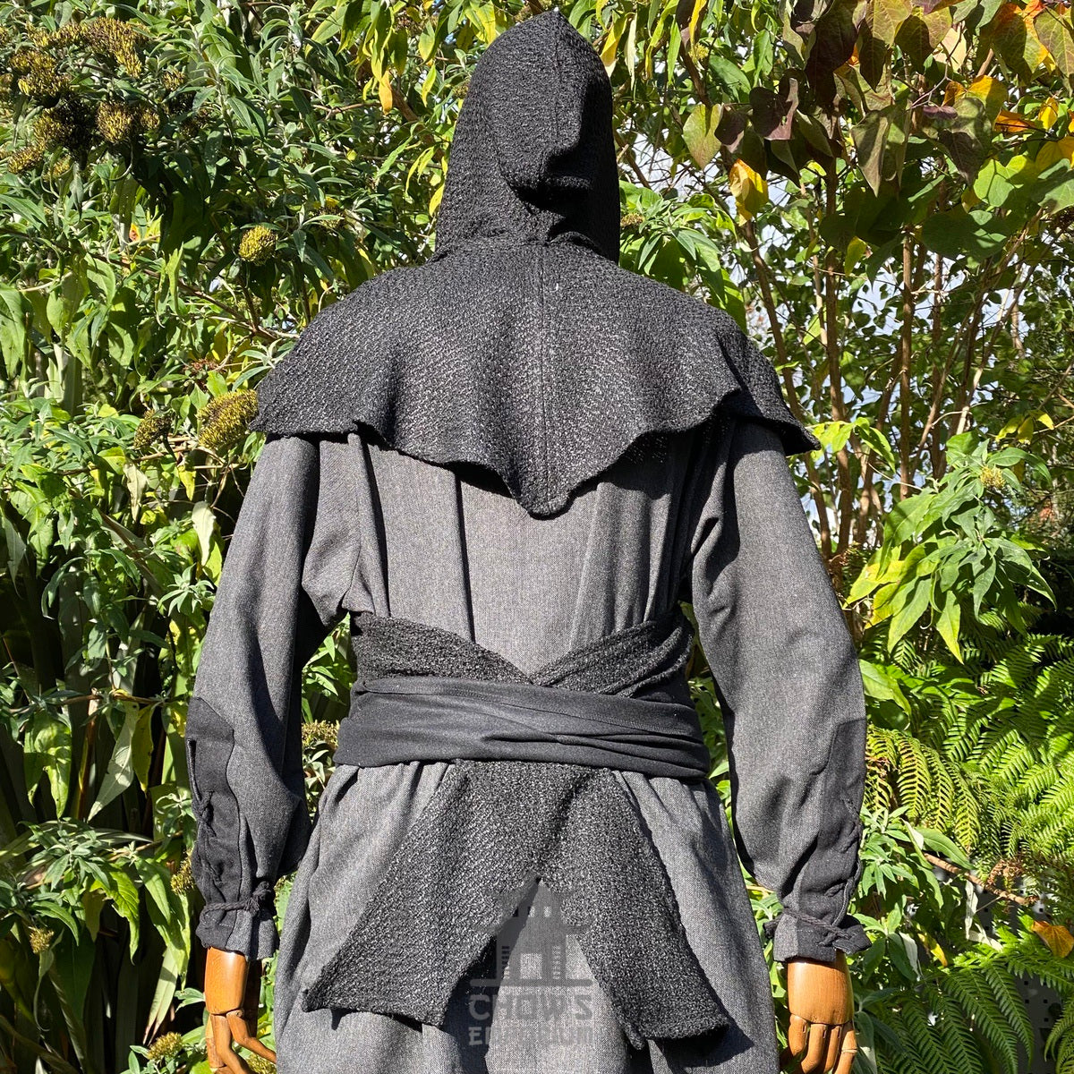 Black wool scarf hood for LARP, seen from the back against greenery.