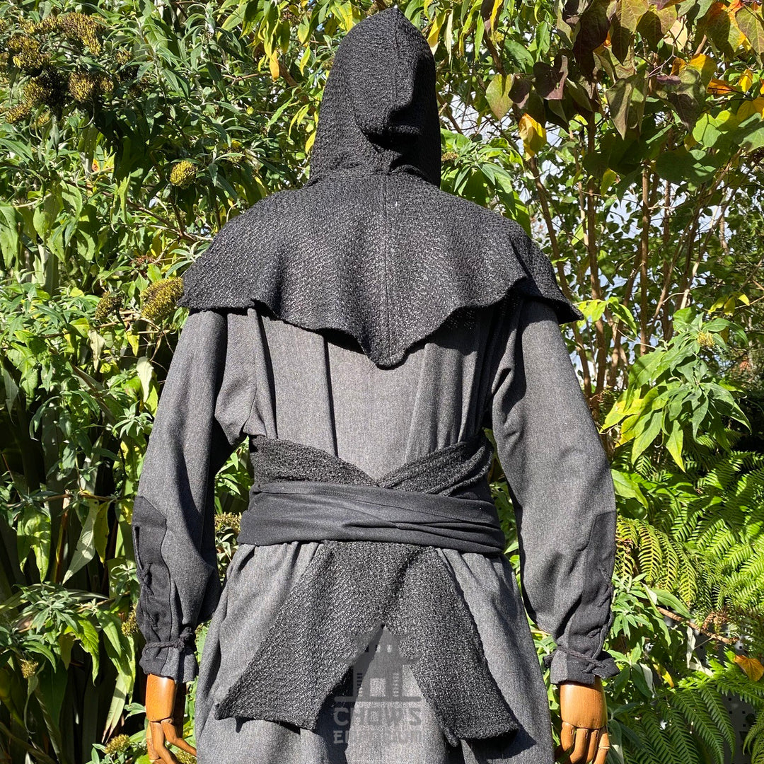 Black wool scarf hood for LARP, seen from the back against greenery.