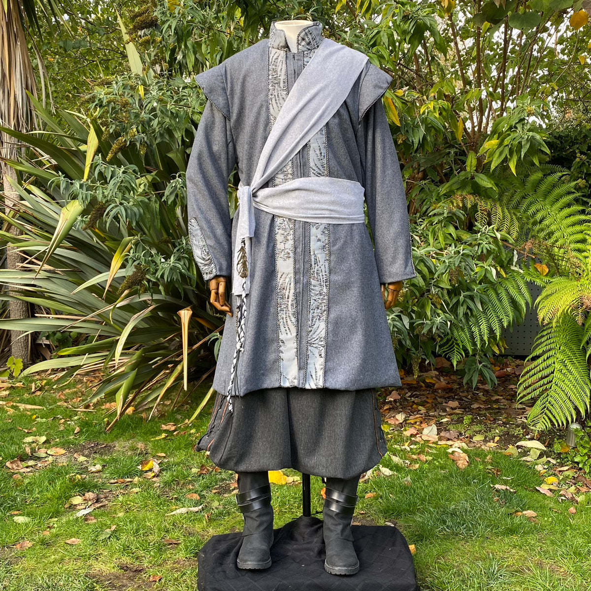 Mannequin in garden wearing grey LARP outfit with sash and detailed trim.