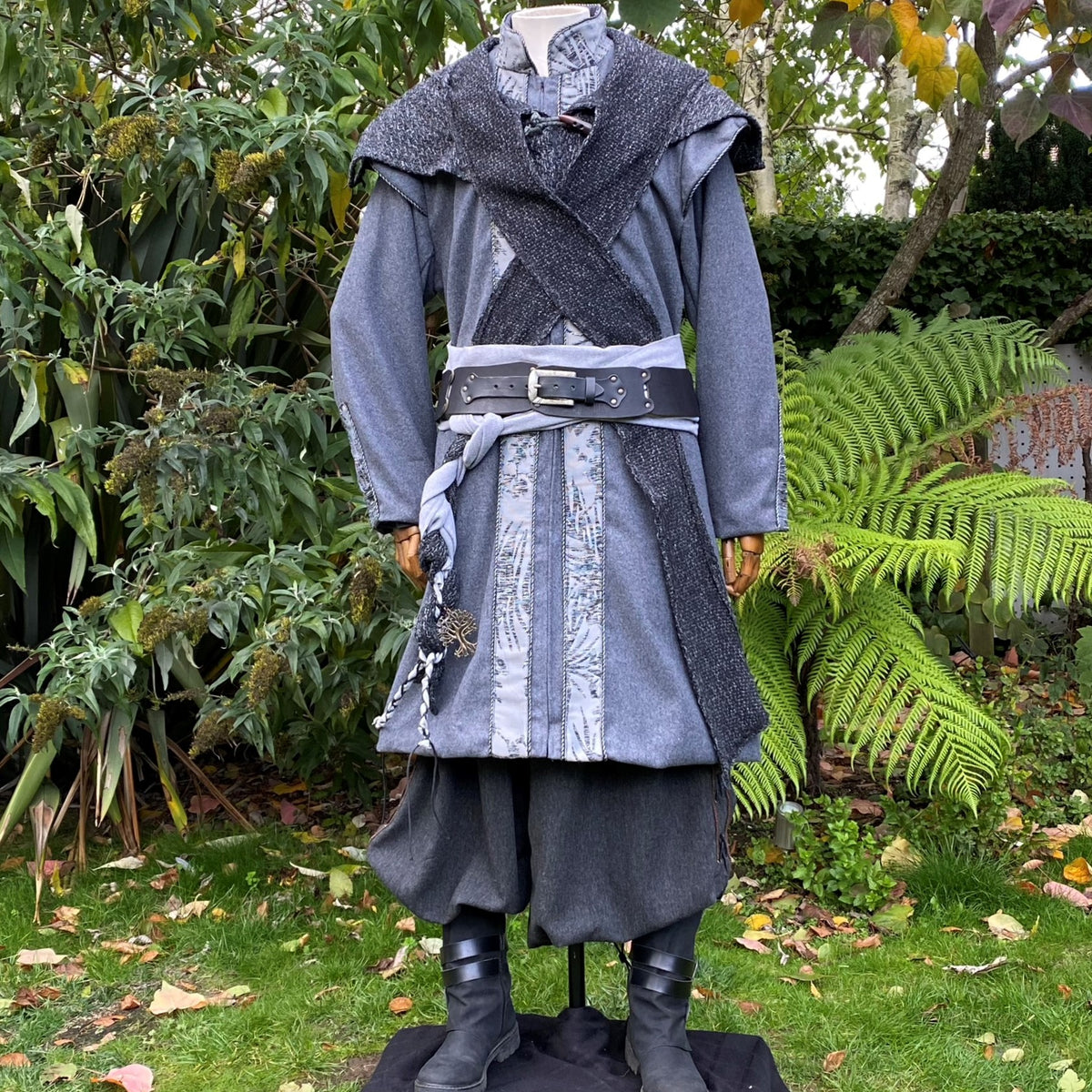 Mannequin in woodland medieval LARP attire, grey coat with cross-lapels.