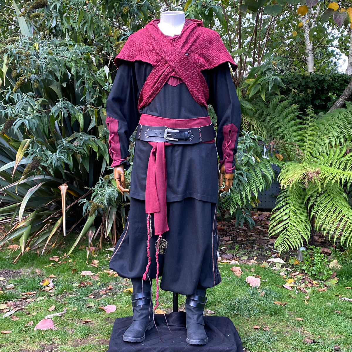 Mannequin in red wool hood and medieval LARP attire, forest backdrop.