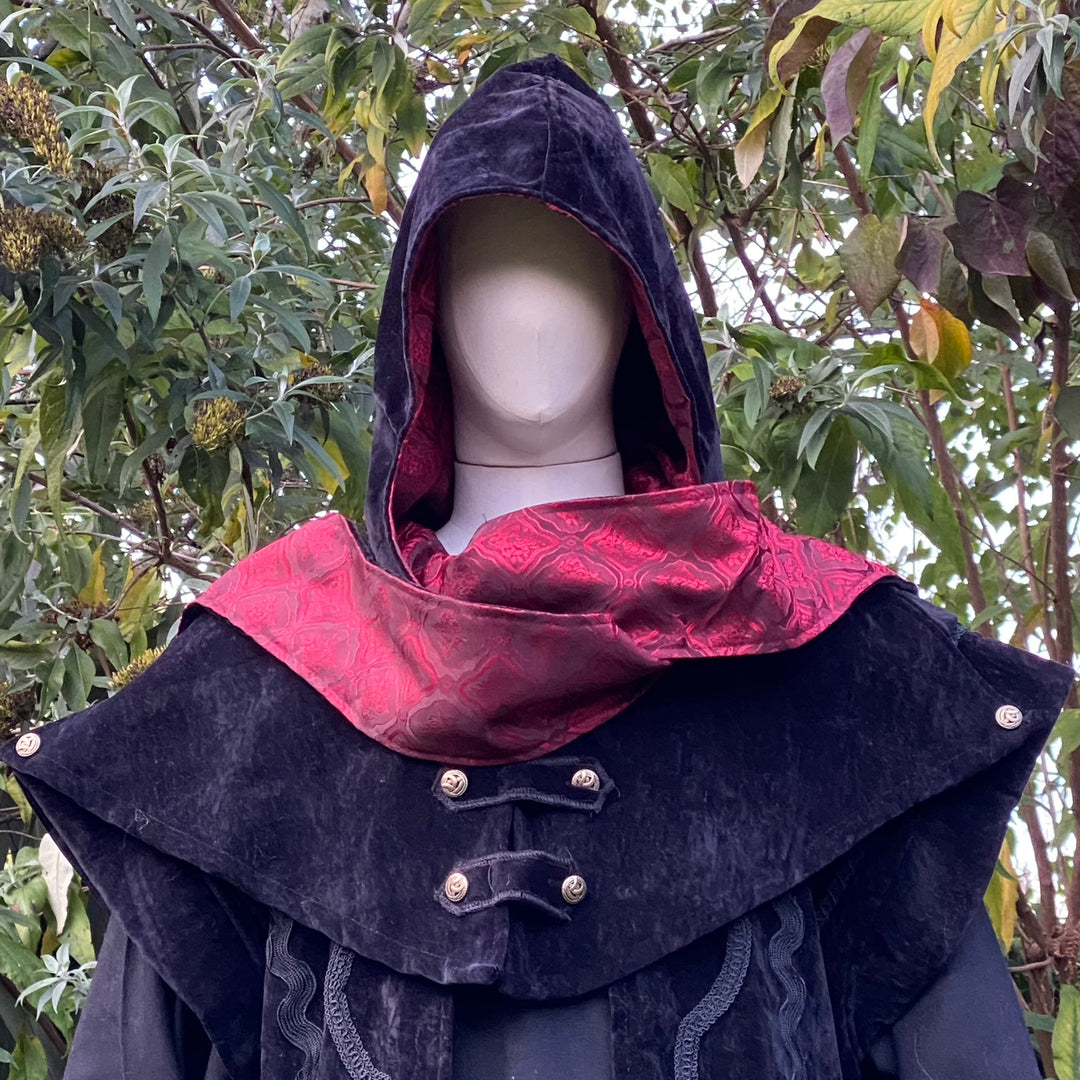 Black velvet LARP hood with red lining, styled against leafy greenery.