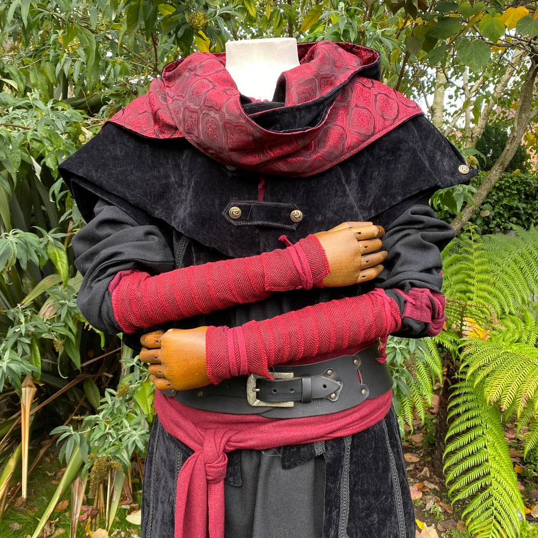 Red herringbone arm wraps for LARP, mannequin wearing black cloak.