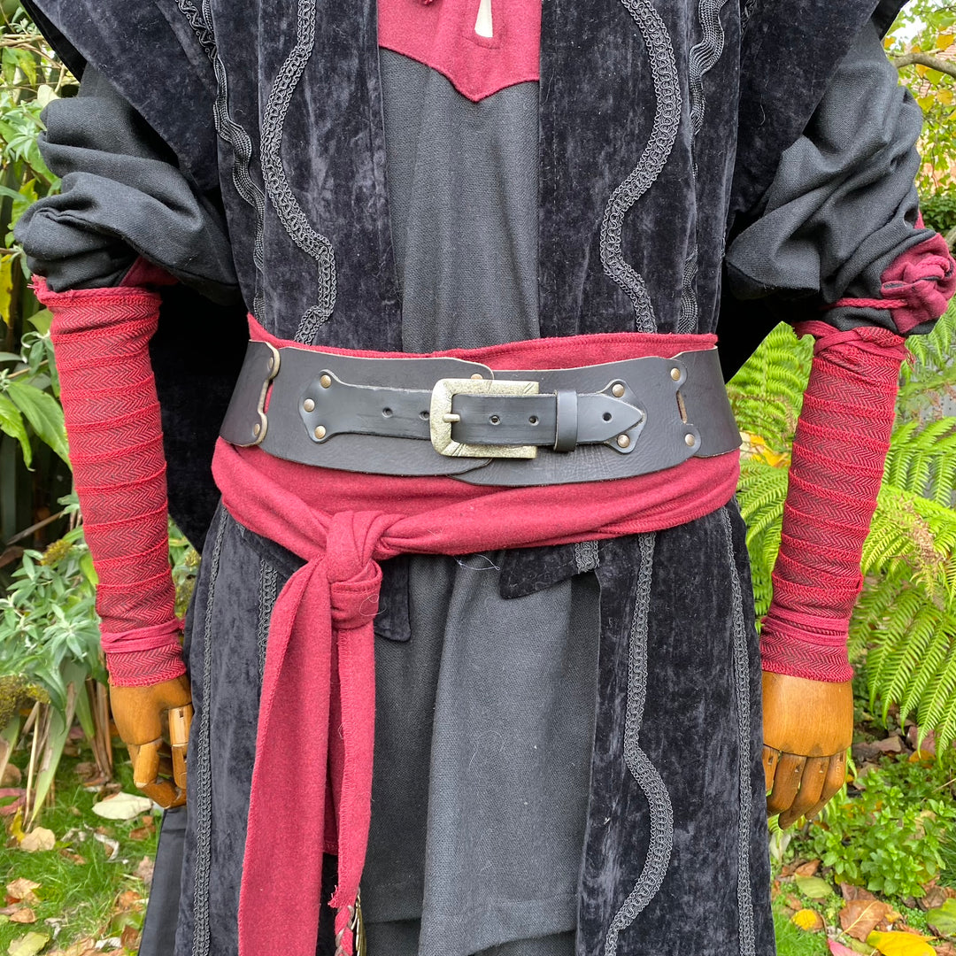 LARP medieval outfit close-up: red herringbone arm wraps, sash tie, black belt.