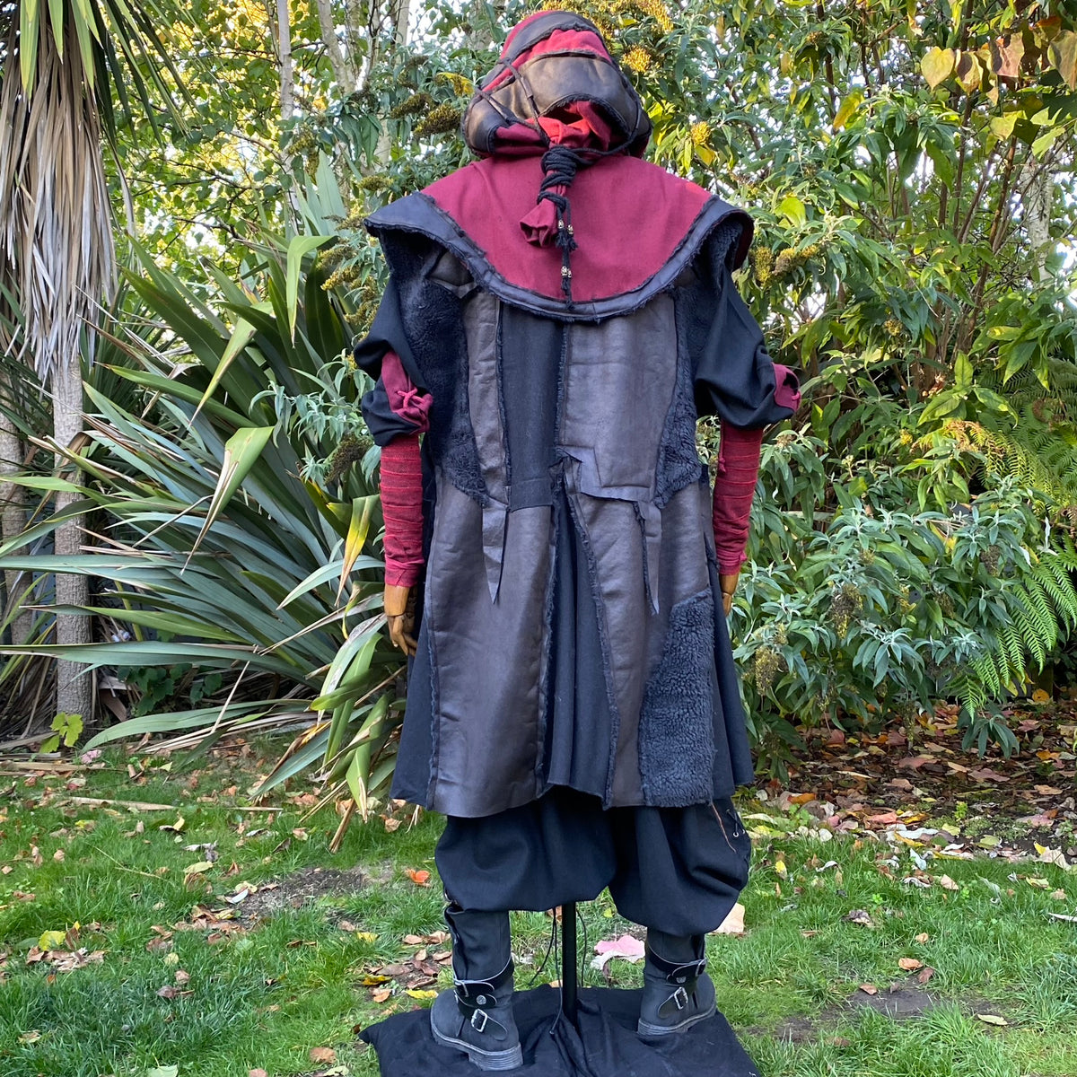 Back view of black faux leather waistcoat for LARP, layered over red tunic.