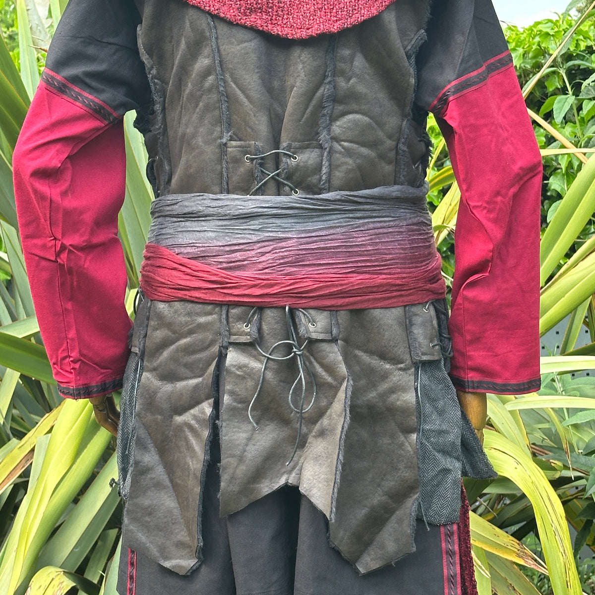 Back view of black and red medieval LARP outfit with sash and hood.