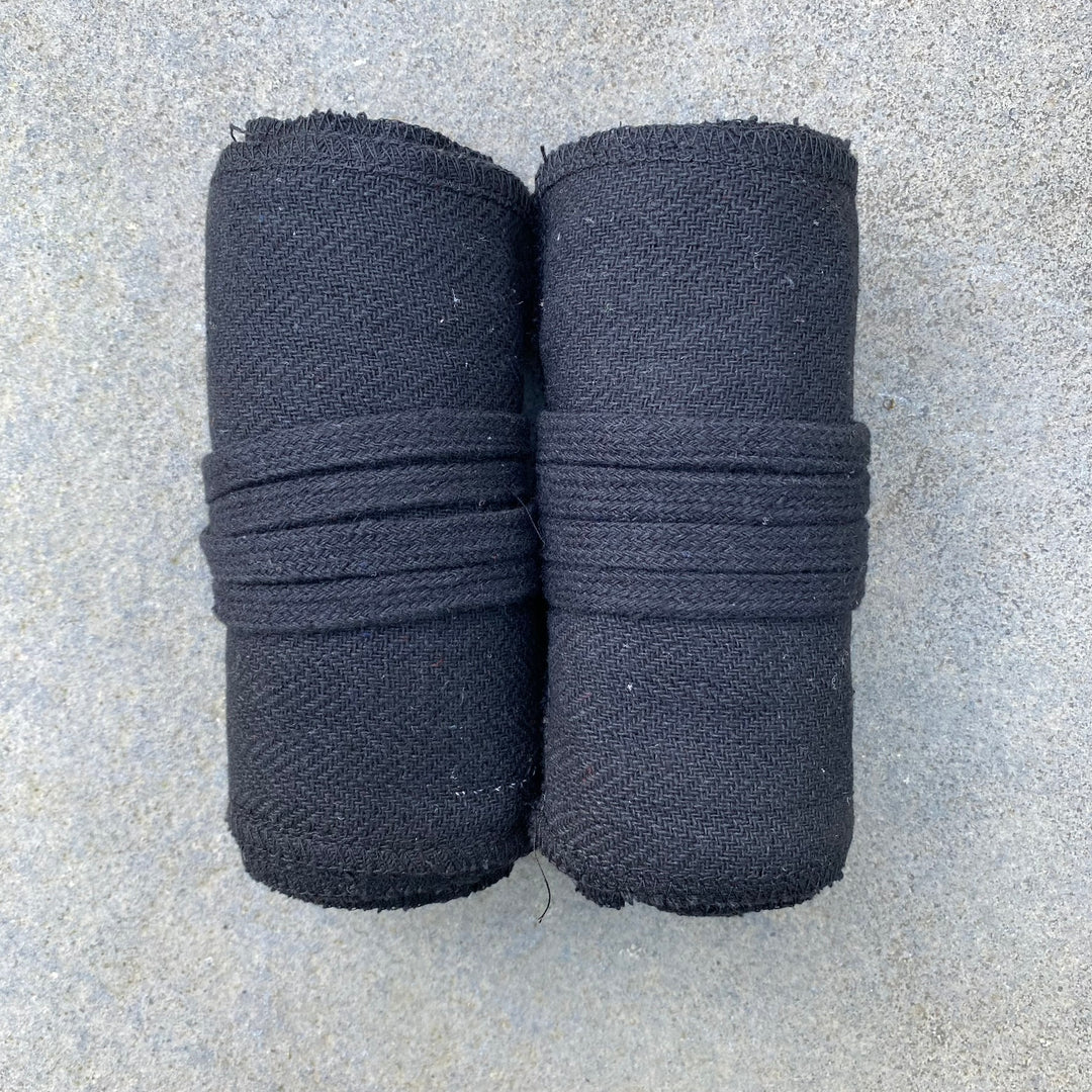 Rolled black herringbone leg wraps for medieval LARP on stone surface.