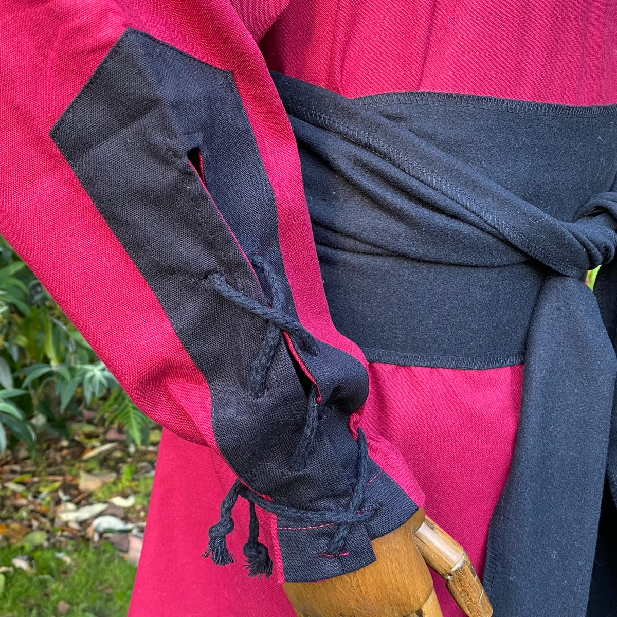 Red and black LARP costume with cloak, shirt, and belt close-up.