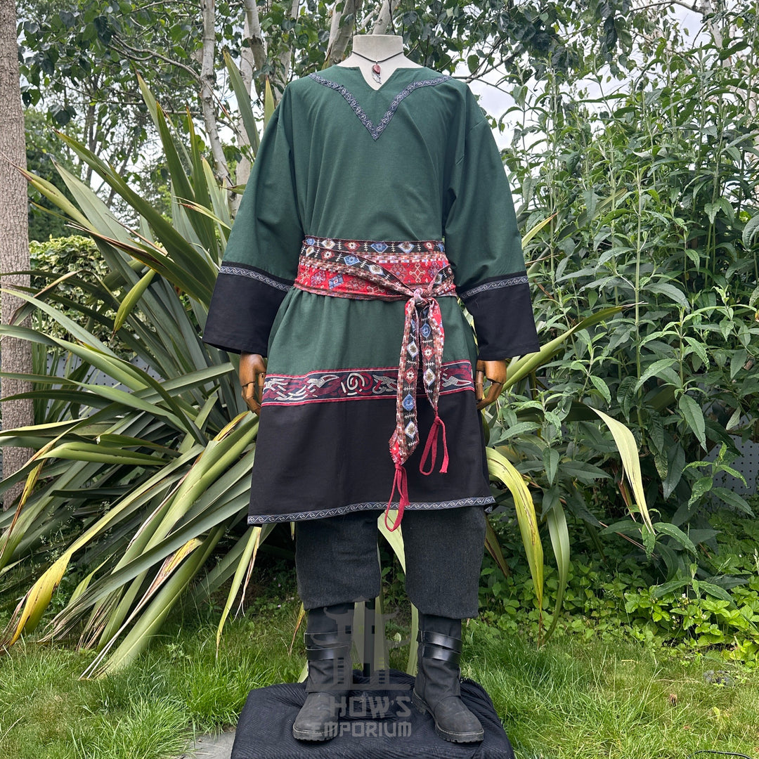 Medieval LARP outfit outdoor, green tunic with red patterned sash and trousers.