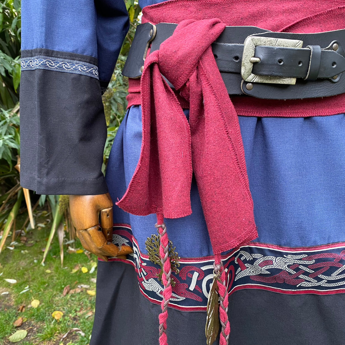 Blue and black LARP medieval tunic with red sash, side view.