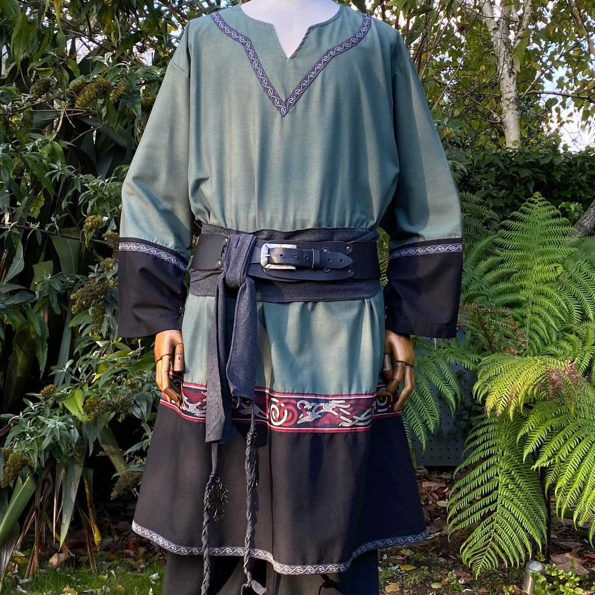 Medieval LARP outfit close-up: green tunic with intricate trim and belt.
