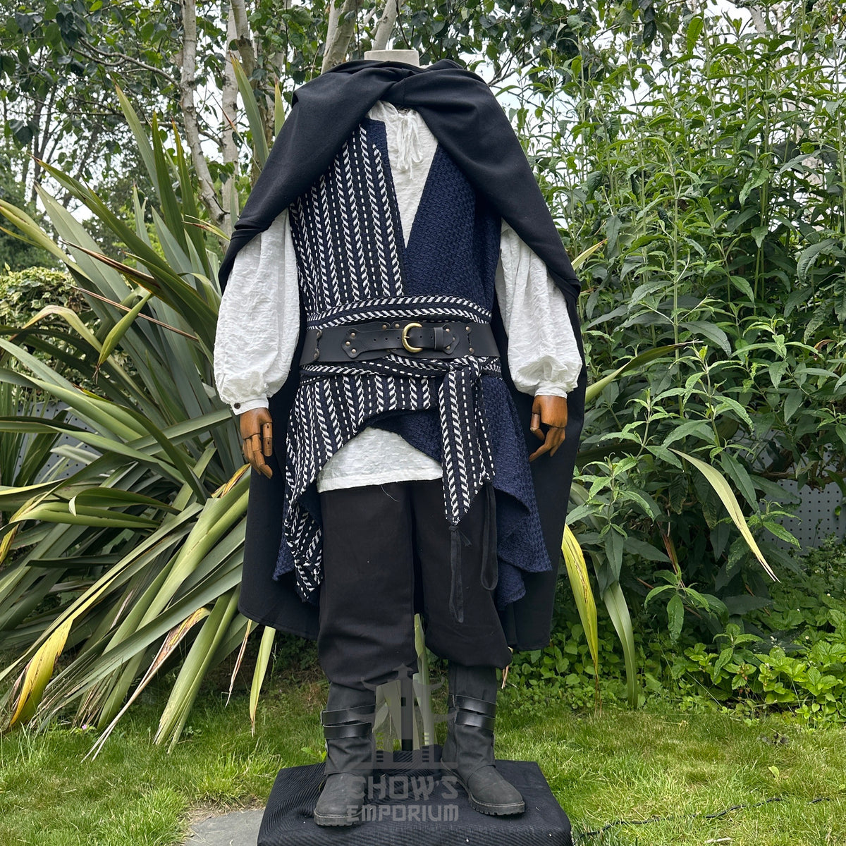 A pirate costume with a black cloak, white shirt, and black pants in an outdoor setting.