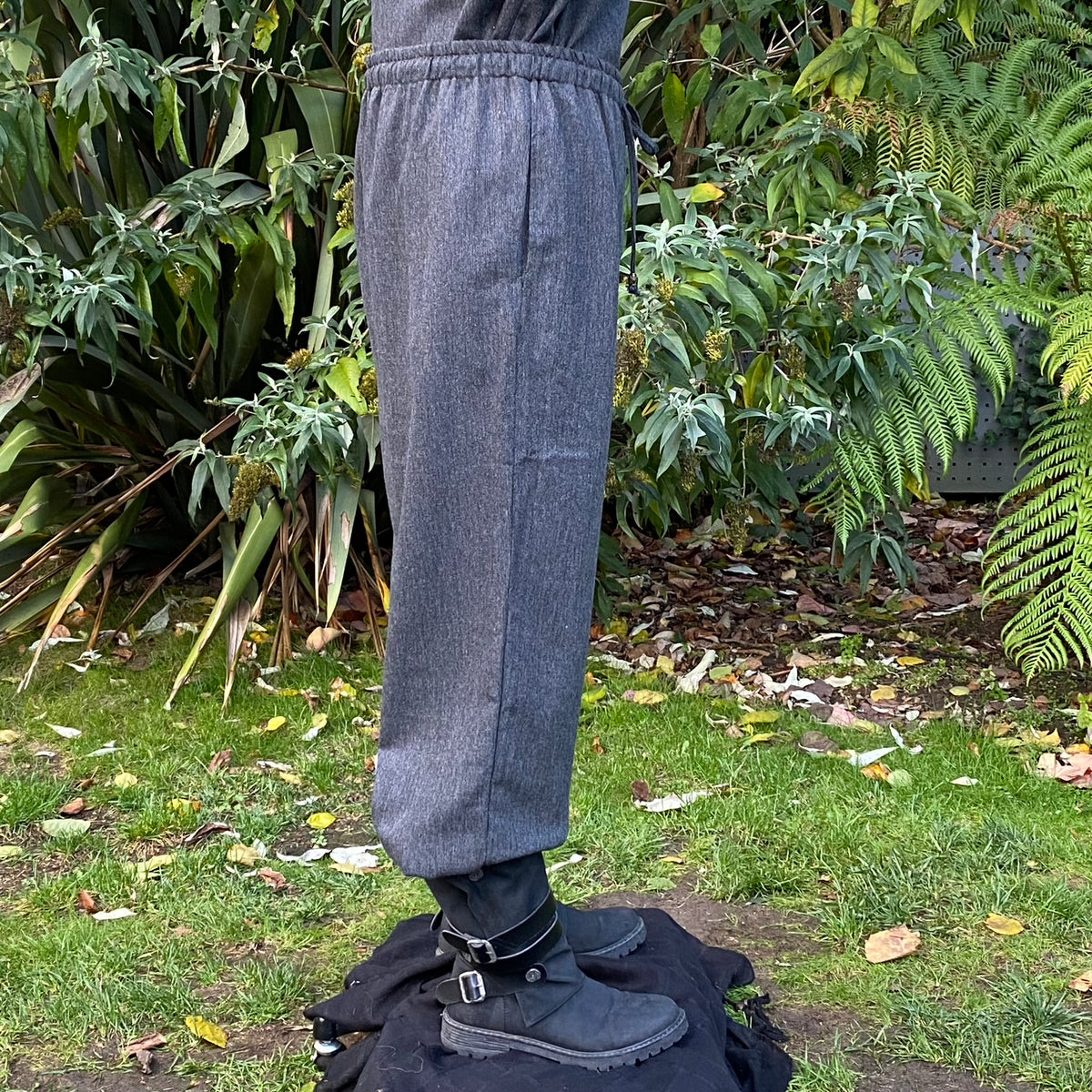 Side view of grey straight-leg medieval pants with wool texture and adjustable cord waist.
