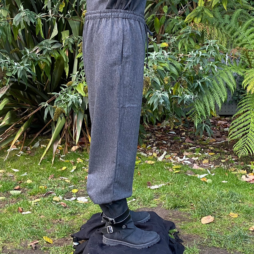 Side view of grey straight-leg medieval pants with wool texture and adjustable cord waist.
